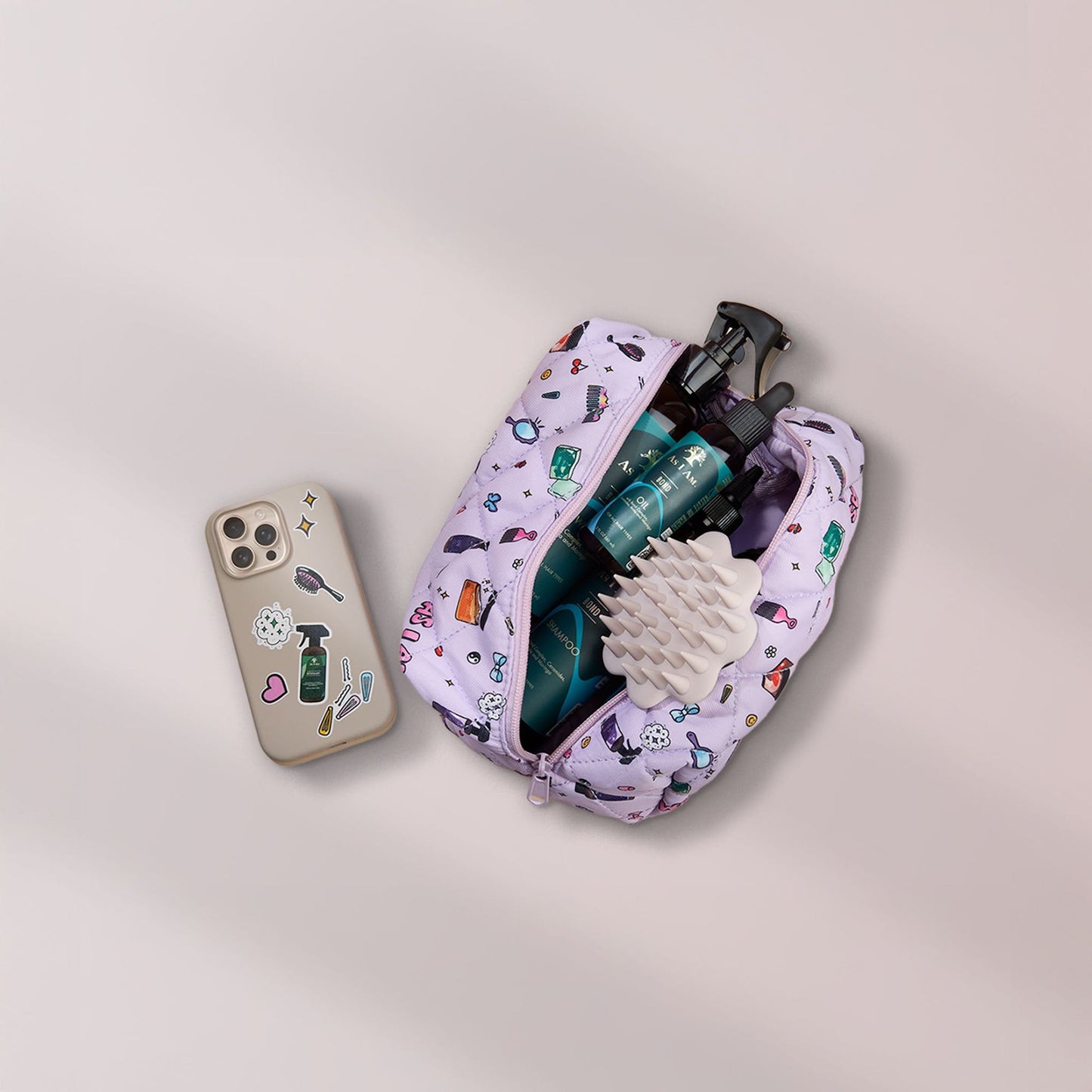 Beige hoofdhuidborstel in cosmetisch tasje met bondproducten en een telefoon