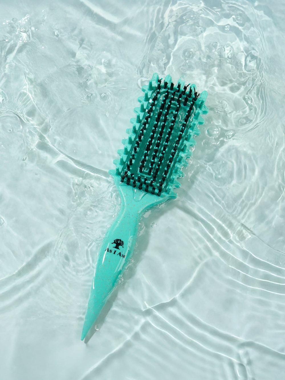 Turquoise haarborstel met zwarte haren op een wit gestructureerd oppervlak