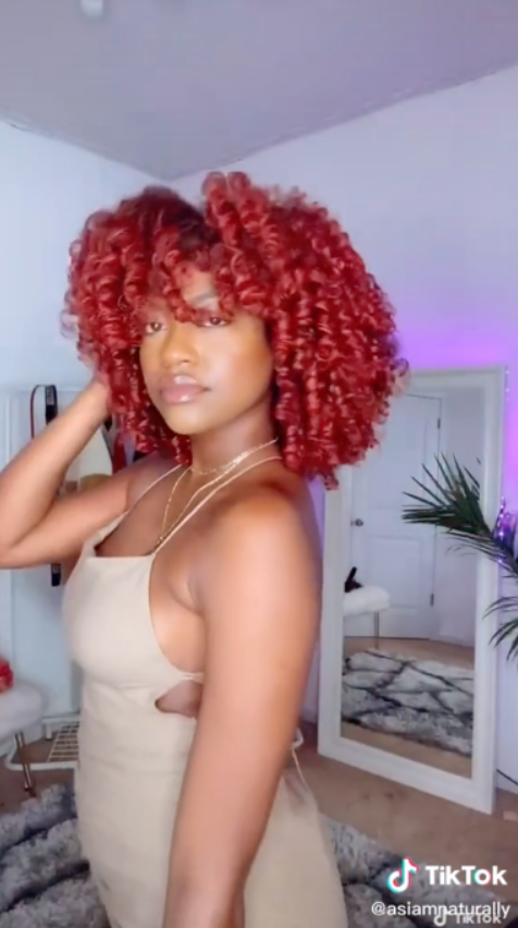 Kimberly Cherrell draagt As I Am Curl Color - met levendige, gedefinieerde krullen, gestyled met tijdelijke haarkleurgel, met opvallend pigment en gezonde glans.