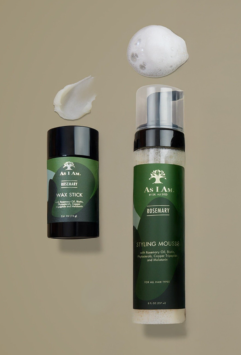 As I Am haarverzorgingsproducten, waaronder een waxstick en stylingmousse op een beige achtergrond
