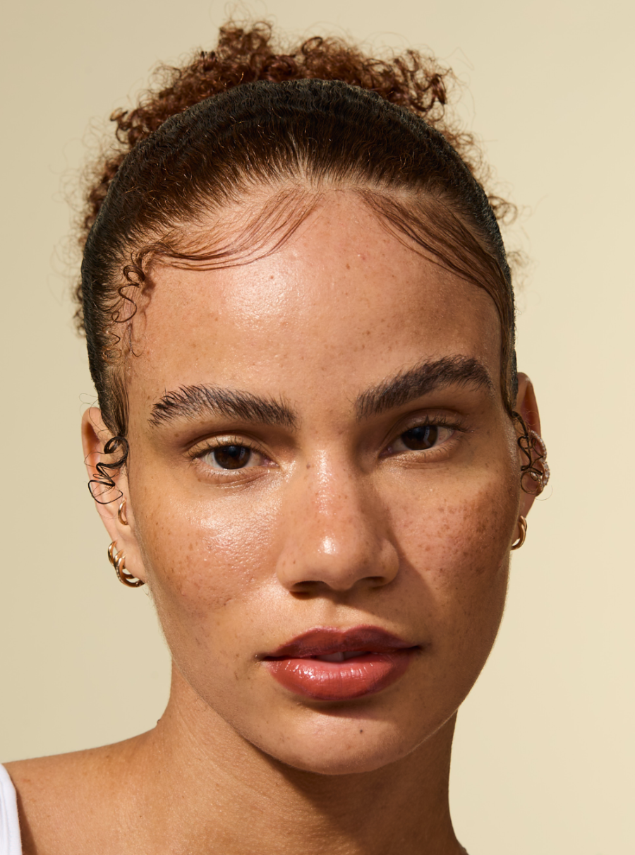 Model met gladde, strakke randen en een gepolijst kapsel gestyled met de AS I AM Rosemary Wax Stick - het haar ziet er glad en pluisvrij uit en wordt stevig op zijn plaats gehouden met een natuurlijk ogende finish.