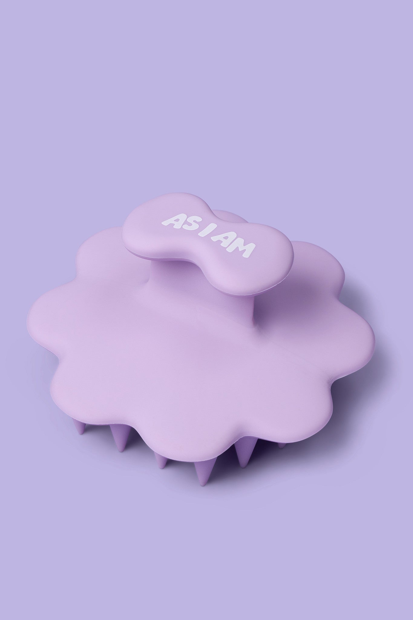 Paarse hoofdhuidmassageapparaat met 'AS I AM' tekst op een lichtpaarse achtergrond